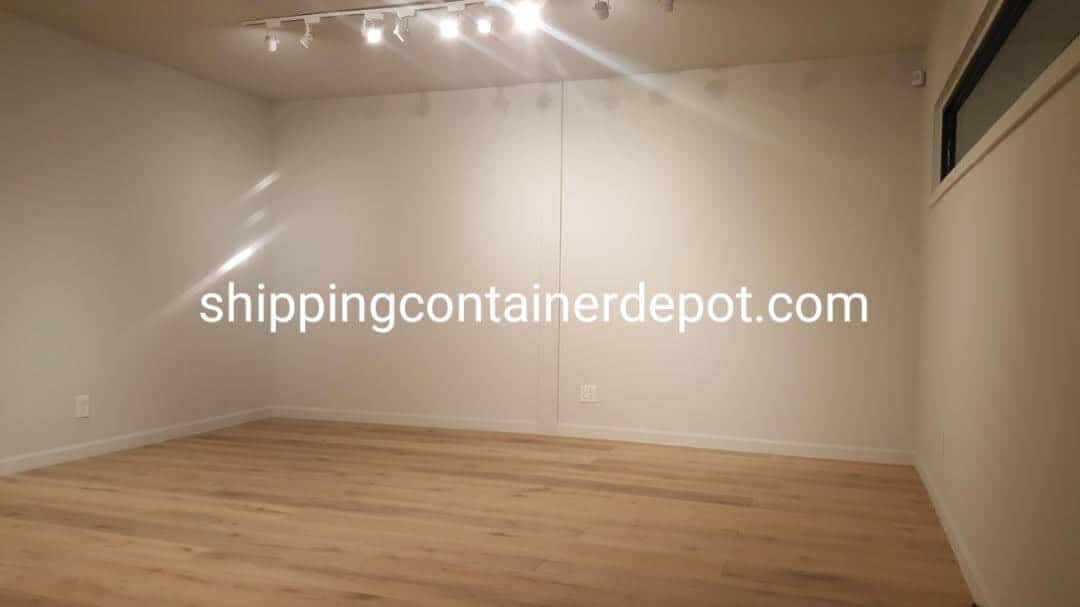 Finished container office interior with wood floor and track lighting